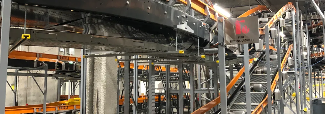 Overhead view of installed baggage conveyor lines and steel support structure inside an airport terminal