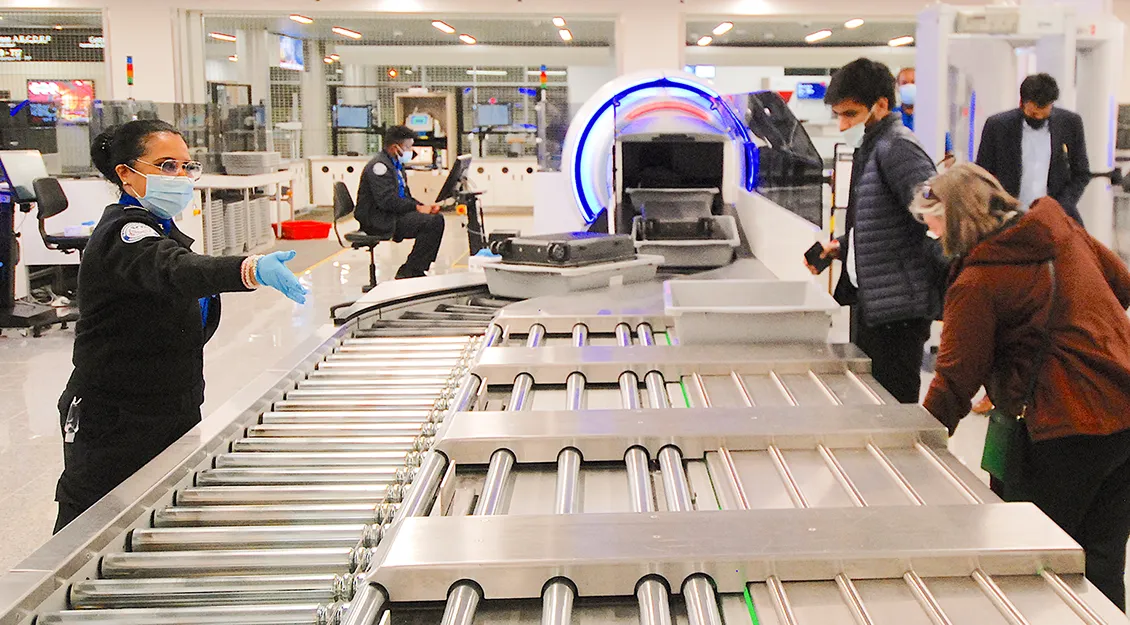 Security checkpoint with an automated screening lane and roller conveyor for passenger bag scanning