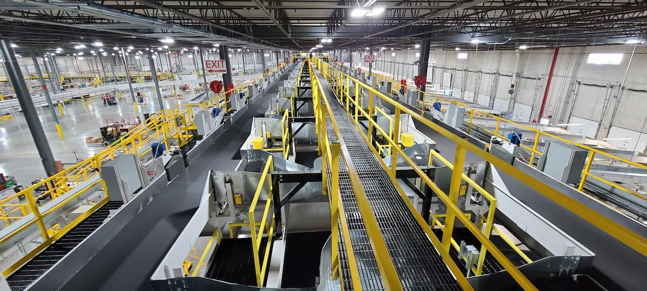 Large parcel sortation facility with elevated conveyor lines and yellow guardrails