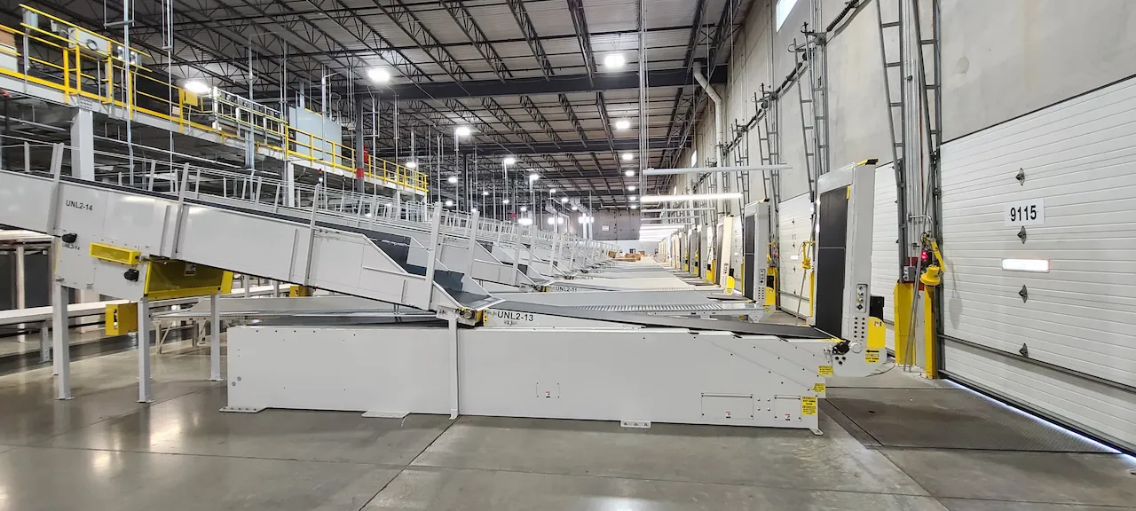 Row of extendable trailer-loading conveyors at warehouse dock doors
